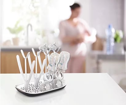 Zdjęcie poglądowe suszarki Philips Avent z butelkami i akcesoriami na kuchennym blacie.