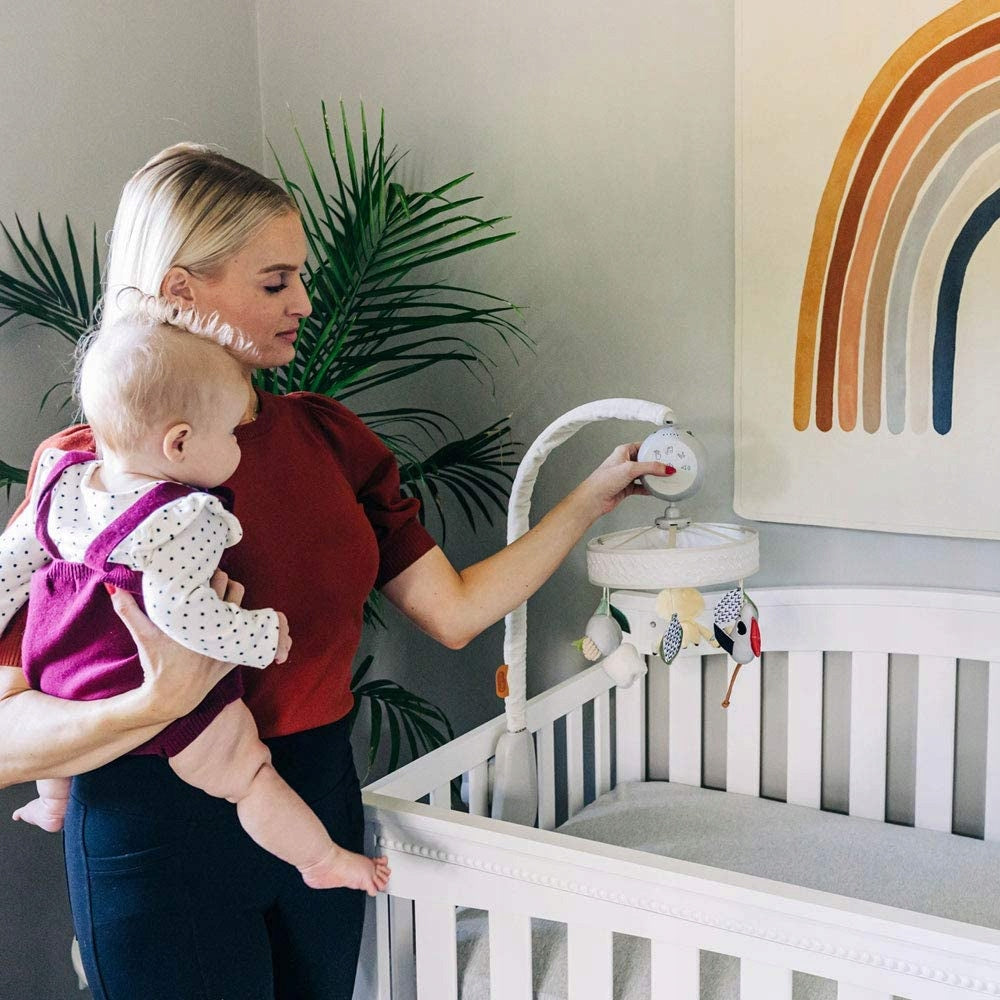 TINY LOVE Boho Chic karuzela do łóżeczka, mama ustawiająca karuzelę nad białym łóżeczkiem z dzieckiem