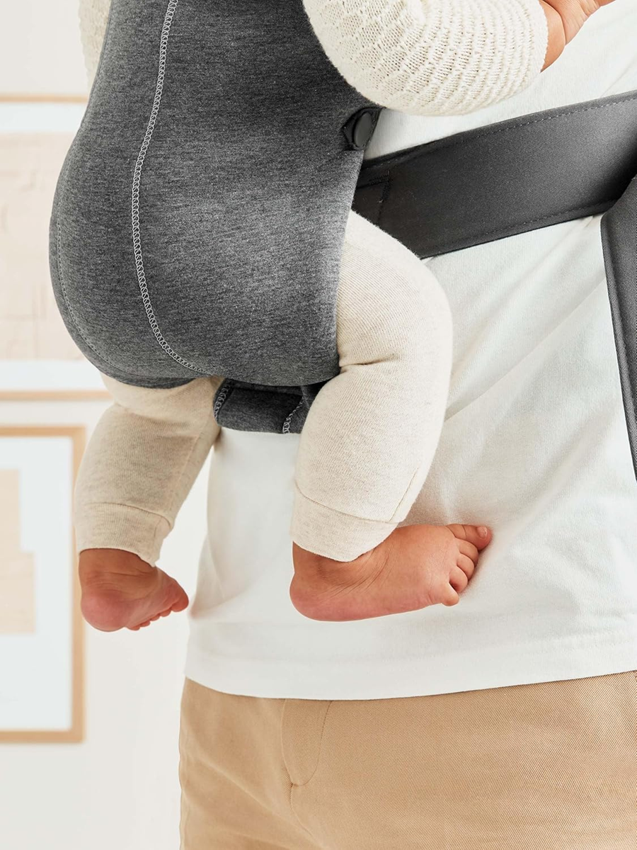 Zbliżenie na dolną część ciemnoszarego nosidełka BabyBjörn Mini 3D Jersey i nogi dziecka.